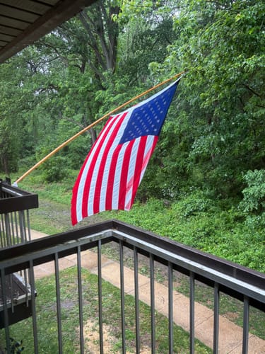 Customer's Heavy Duty American Nylon Flag seen from a balcony, hanging damply in the rain.