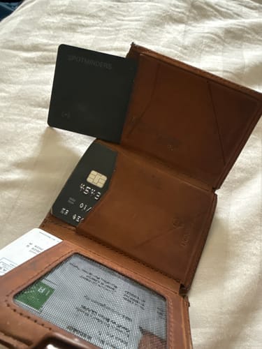Customer's SPOTMINDERS Tracking Card shown partially inside a brown wallet, demonstrating its slim fit.