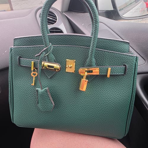 A customer's green pebbled handbag with gold-tone hardware, resting on their lap.