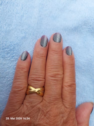 Hand einer Kundin mit den aufgetragenen, schimmernden 'Fuchsia Ombré Cateye' UV-Gel-Nagelfolien.