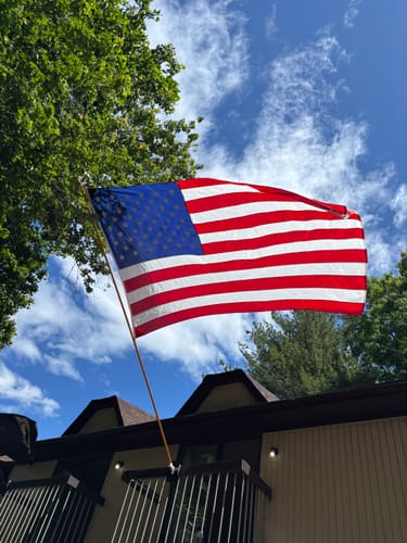 Customer's Heavy Duty American Nylon Flag waving in the wind against a sunny sky with clouds.