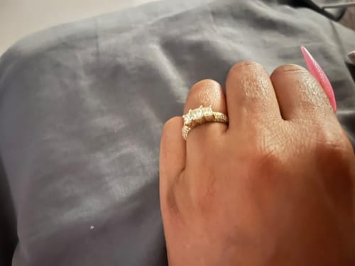Customer's hand wearing the sparkling three-stone diamond ring with a pavé gold band.