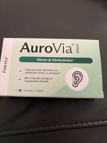 Rezensent zeigt die Verpackung von AuroVia intens für Ohren & Hörfunktion auf einem Tisch.