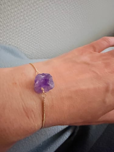 Une cliente portant le bracelet Améthyste "Brut" à son poignet, mettant en valeur la pierre et la fine chaîne.