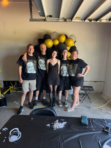 Customer and a group wearing matching personalized black senior shirts with a baby photo at a party.