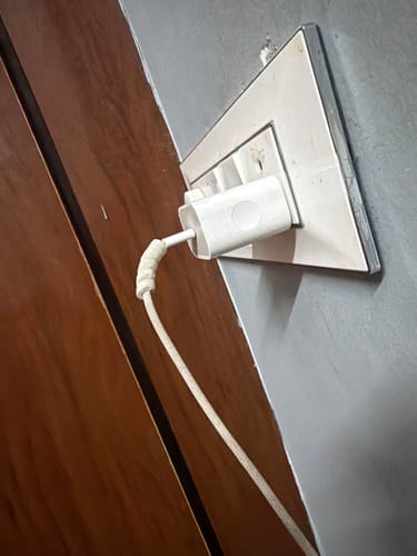 Customer's white cable protector shown in use on a charging cable plugged into a wall socket.