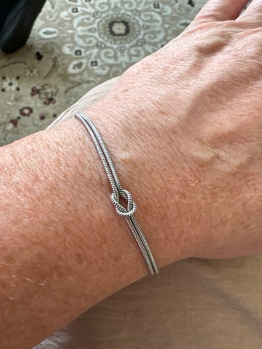 Customer showing a silver-colored bracelet with a knot design on their wrist.
