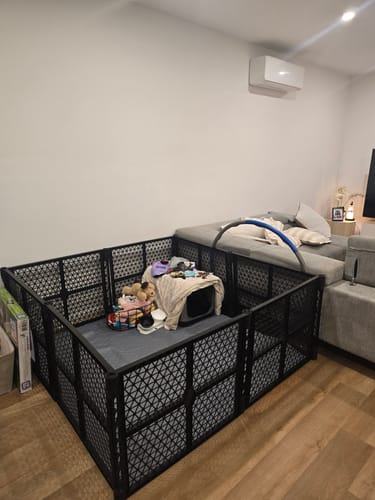 Customer's black puppy pen set up indoors, containing a crate, mat, and toys.