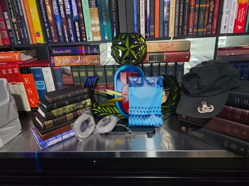 Reviewer's new Focal Clear Ear Pads in their plastic packaging on a desk with books and a hat.