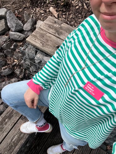 Rezensent trägt das grün-weiß gestreifte Longsleeve DOPAMINE mit pinkem Kragen und Bündchen im Freien.