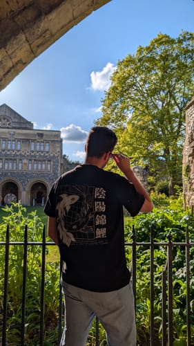 Customer from behind wearing the black Ying Yang Koi T-Shirt outdoors, showing the detailed back graphic.