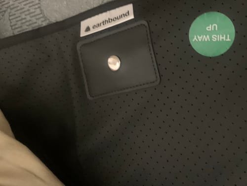 Close-up of the Earthbound pad showing the brand tag, metal connection snap, and a 'THIS WAY UP' sticker.