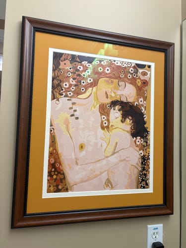 Reviewer's finished Mother and Child paint-by-numbers artwork, framed and hanging on a wall.