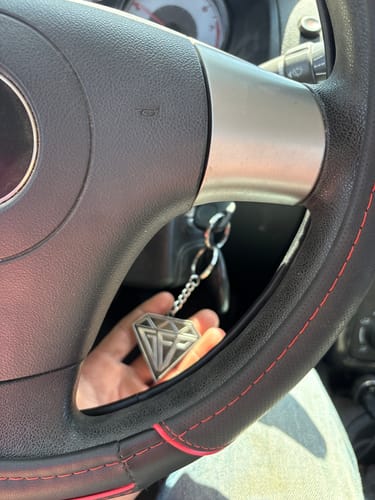 Customer holding their Diamond Keychain on a key in their car's ignition.