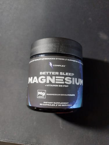 A customer's black jar of Better Sleep Magnesium supplement on a dark surface.