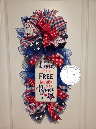 Customer's patriotic door swag using the Printed Stars ribbon in bows, set against blue mesh.