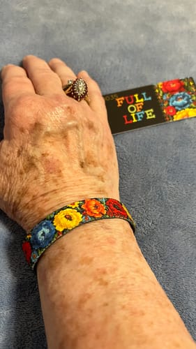 Customer wearing the Full of Life Bracelet with the colorful floral side displayed on their wrist.