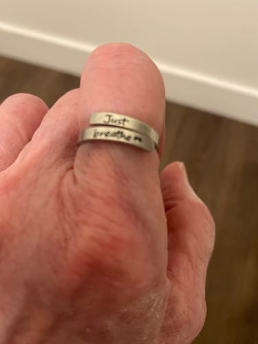 Reviewer's close-up of the Just Breathe Ring on their thumb, showing the 'Just breathe' engraving.