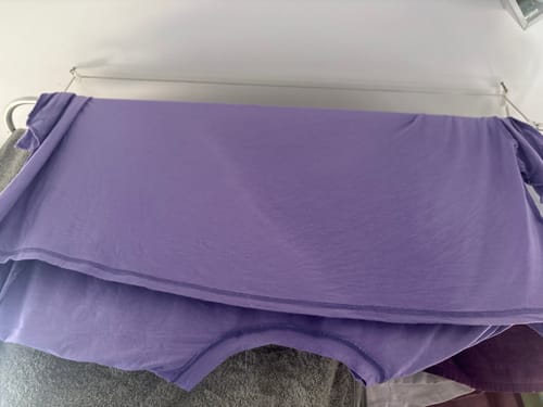 Cliente mostrando sua Camisola Livro roxa pendurada em um varal.
