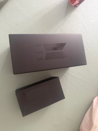 Customer's black packaging boxes for the BTS Official Light Stick Ver.4 and cradle on a flat surface.