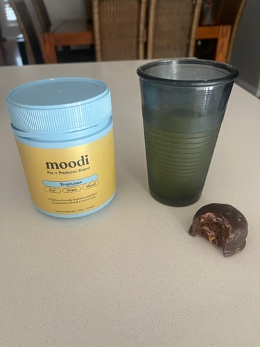 Reviewer's bitten Choc Caramel Plant Protein Ball on a counter next to a drink.