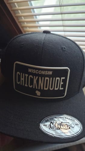 Customer's black Wisconsin Blackout Plate Hat with a custom license plate patch that reads 'CHICKNDUDE'.