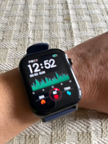 Reviewer's Health smartwatch on their wrist, displaying the time and a green health data graph.