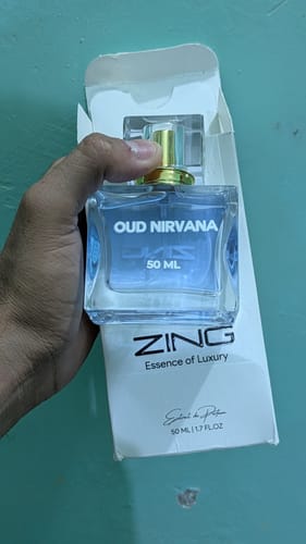 Customer holding the new Oud - Nirvana 50ml fragrance bottle in front of its white packaging.