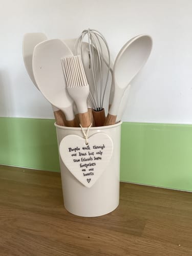 Customer's white silicone utensil set with wooden handles, displayed in a matching pot on a kitchen counter.