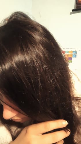 Clienta muestra su cabello oscuro, liso y brillante después de usar el tratamiento de Polvo de Cassia.
