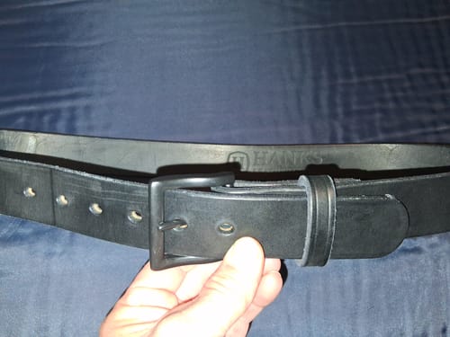 Close-up of a customer holding their black leather Everyday belt, showing the matte black buckle and interior.
