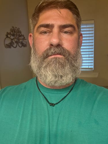 Reviewer wearing the black Legacy Necklace with small beads against a green shirt.