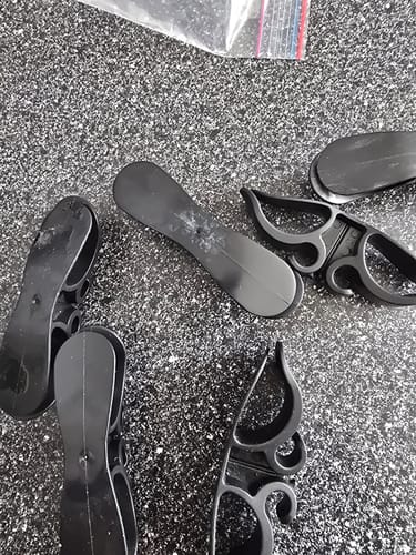 Customer's black appliance cord organizers scattered on a counter, showing the backs without adhesive pads.