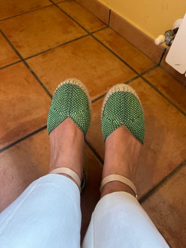 Una clienta lleva puestas las alpargatas Valvanera Verde, mostrando el tejido verde y la pulsera beige del tobillo.