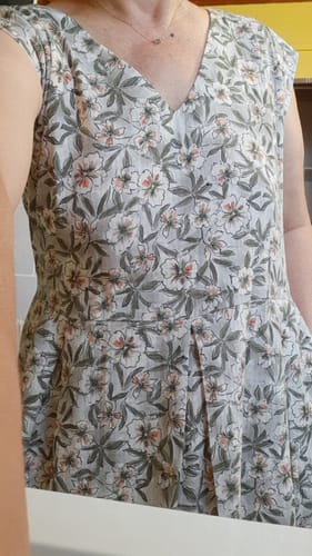 Gros plan d'une cliente portant la Robe Louison, montrant son motif végétal, son col en V et les plis.