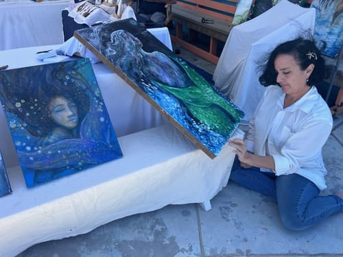 Reviewer displaying their paintings at an art stall, showing the creative outlet mentioned in their review.
