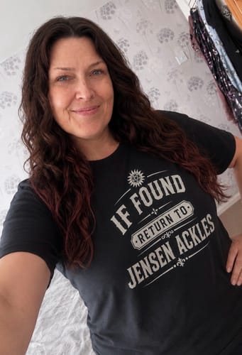 Reviewer smiling while wearing the black Unisex T-Shirt with its printed fan design.
