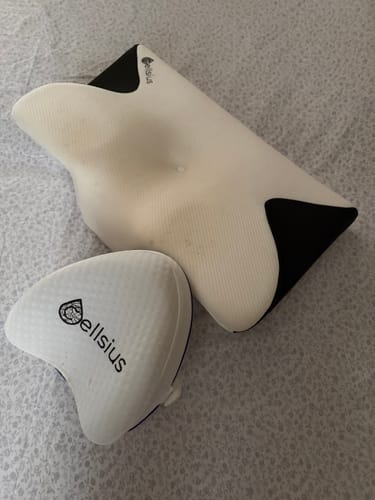 Avis d'un client : l'Oreiller Papillon Cervical Cellsius et le coussin pour genoux posés sur un lit.