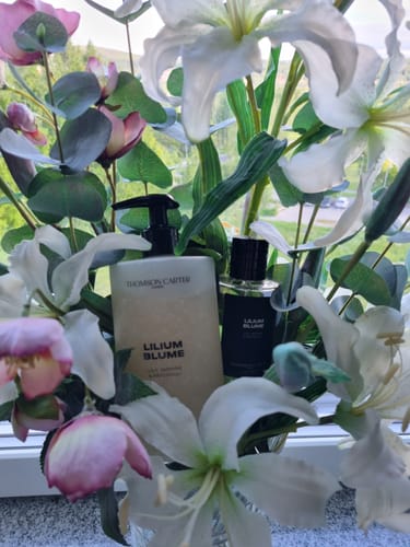 Customer's Lilium Blume Body Wash and perfume set amongst white lilies, reflecting the product's floral scent.