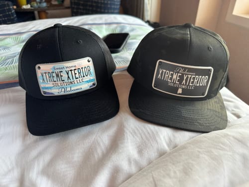 Customer's two black hats with customized Alabama license plate patches. One is a blackout design and the other is full-color.