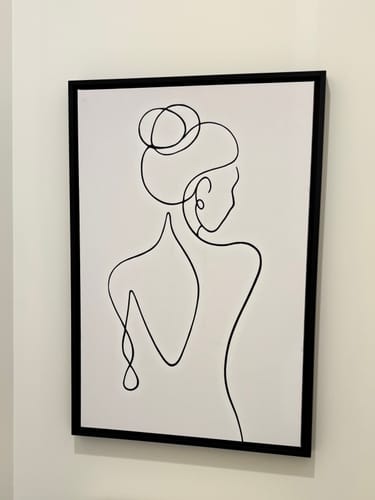 Customer's Woman With Her Back Turned Line Art in a black frame, hung on a wall.
