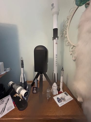 Customer's Starship Flight 12 pin displayed in its packaging among a collection of rocket models on a desk.