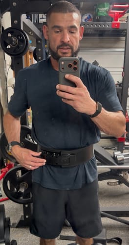 Reviewer adjusting their new black Ratchet Lever Belt while wearing it in a gym.