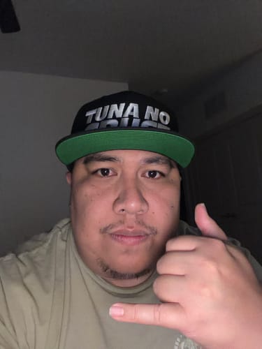 Reviewer wearing the black 'Tuna No Crust' snap back hat with a green under-bill.