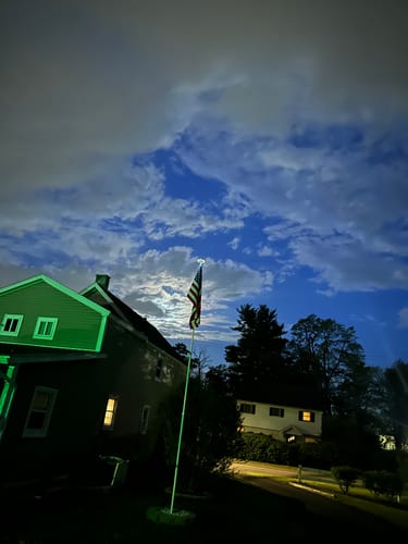 Customer's American Nylon Flag on an illuminated pole in a yard under a cloudy night sky.