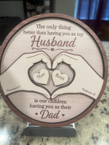 Customer's personalized 2-layered wooden plaque with hands forming a heart around two smaller hearts engraved with names.