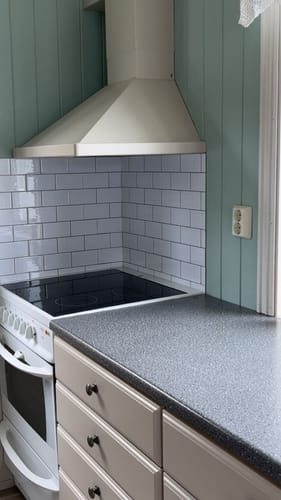 Anmelderens hvite selvklebende subwayfliser montert som en stilig backsplash på et kjøkken.