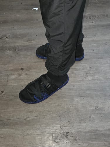 Close-up of a customer wearing the black slides with adjustable straps and socks.