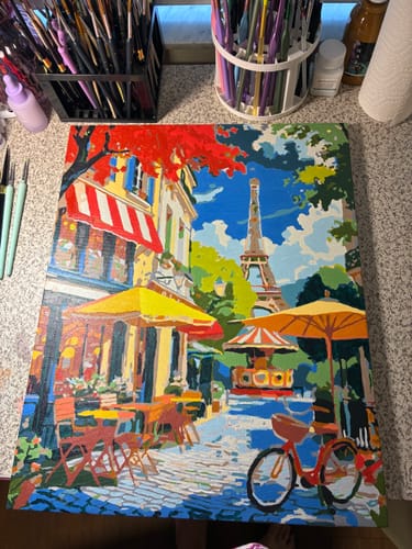 Customer's in-progress painting from the Parisian Street Café kit showing the Eiffel Tower and a red bicycle.