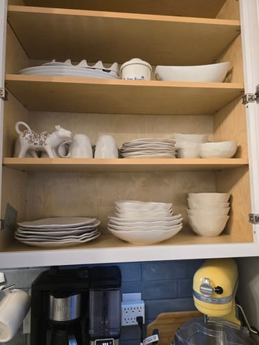 Customer's Stoneware Deep Plate Set in pearl white, stacked inside a wooden kitchen cabinet.